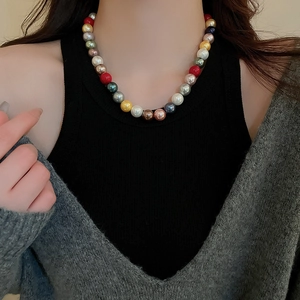Close-up of a colorful round pearl necklace worn by a model against a dark background