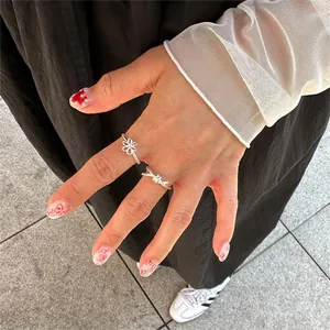 Detailed view of S925 sterling silver knotted ring and hollow flower band on fingers