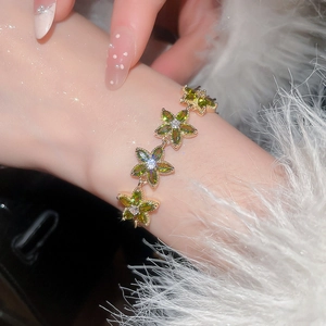 Close-up of elegant gold flower bracelet with olive green marquise-cut zircons