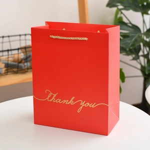 Macro shot of red gift bag with golden Thank you text and braided rope handles