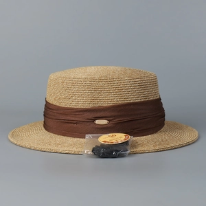 Détail d'un chapeau de paille avec ruban plissé café et étiquette de protection UPF 50+