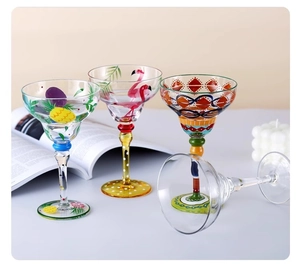 Close-up of hand-painted margarita cocktail glasses with pineapple and flamingo designs