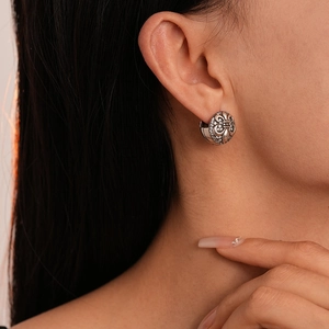 Detail of vintage fleur-de-lis silver earrings with zircon stones worn by a model