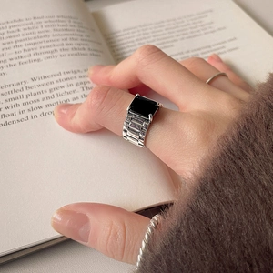 Detail of 925 silver belt-style ring with black gemstone worn on a hand over a book