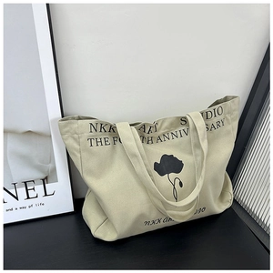 Macro detail of beige canvas tote bag with floral prints and thick shoulder strap