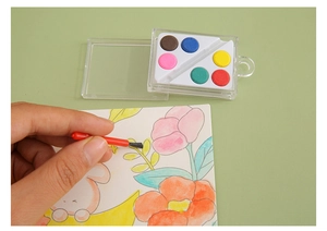 Detailed view of hand using mini brush with 6-color solid watercolor paint set for DIY art