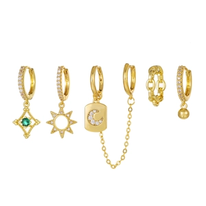 Golden moon and star earring set with green gems and tassel chains on white background