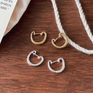 Macro view of gold and silver U-shaped hoop earrings on a rustic wooden surface