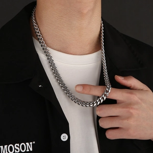 Close-up of polished silver stainless steel Cuban link chain necklace on male model neck