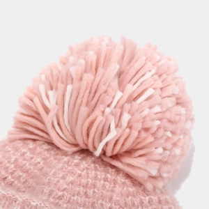 Detail of pink and white faux fur pom-poms on thick knit winter hat for women