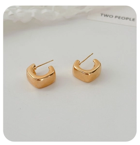 Close-up of golden square geometric hoop earrings with a high-polished metallic finish