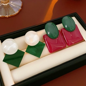 Detailed macro view of resin geometric earrings with green and red square pendants