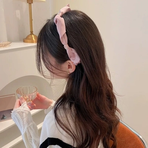 Dettaglio cerchietto in tessuto rosa con design intrecciato e decorazione di perle