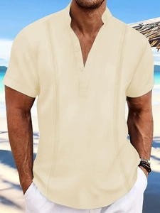 Detail of men's beige polo shirt with vertical pleats and five buttons on seaside beach