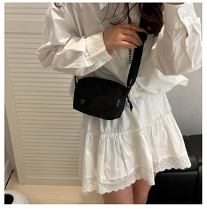 Dettaglio di una borsa a tracolla nera minimalista in nylon con tracolla regolabile indossata