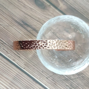 Detail of rose gold magnetic copper bracelet featuring textured hammered surface finish