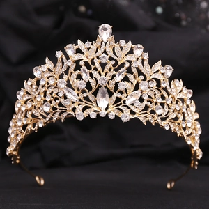 Close-up of golden bridal crown with sparkling clear crystals on black luxury fabric
