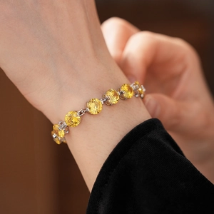 Close-up of yellow round zircon bracelet with silver-tone prong setting on wrist