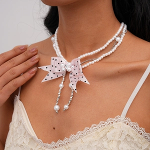 Detail of double-layer pearl necklace with pink polka dot ribbon bow and fringe