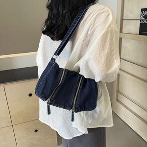 Large capacity dark blue denim tote bag with double zippers worn by a model in casual style