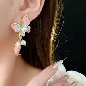 Dettaglio di orecchini a farfalla vintage con perla e pendente a fiore rosa sul modello