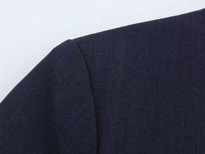 Detailed close-up of dark blue twill fabric shoulder and sleeve seam of a blazer