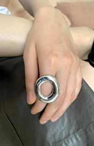 Close-up of a chunky silver irregular metal ring worn on index finger with mirror finish
