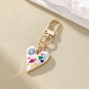 Macro detail of heart-shaped graffiti keychain with evil eye pattern and gold spring clasp