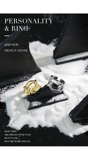 Macro detail of gold and silver chunky chain link rings on dark textured rock surface