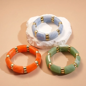 Detail of three acrylic beaded stretch bracelets with marble texture and gold metal spacers