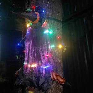 Close-up of glowing Halloween witch tree hugger with purple hair and colorful LED lights