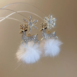 Macro detail of Christmas deer earrings featuring sparkly rhinestones and white fur balls