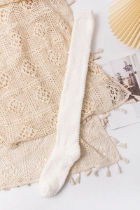 Close-up of soft white coral fleece thigh-high socks with cozy knitted texture detail
