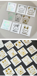 Detailed macro view of cartoon animal stickers with gold and laser finish on gray background