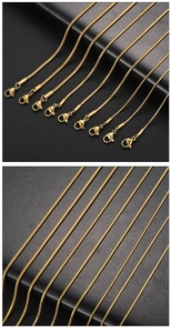 Detail of ten golden round snake bone chains with lobster clasps on black leather background