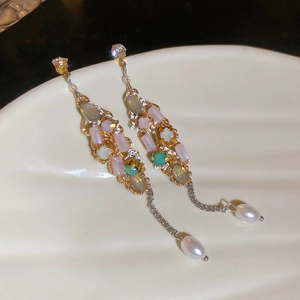 Detail of vintage gold earrings with long tassels, colorful stones and drop pearls