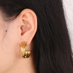 Close-up of a gold-plated titanium steel C-shaped twisted earring worn by a model