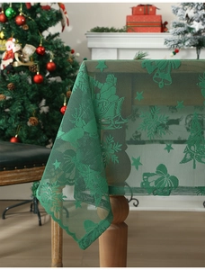 Detail of green lace Christmas tablecloth with Santa, snowflake, and bell patterns