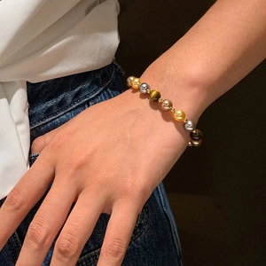 Détail d'un bracelet en perles avec œil de tigre et perles sur un poignet de femme