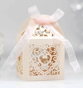 Detailed laser cut heart pattern on cream wedding candy box with pink ribbon bow