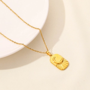 Macro detail of 18k gold plated moon and sunburst rectangular pendant necklace