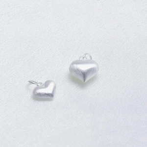 Brushed S925 sterling silver heart pendants in two sizes on white silk background