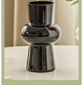 Detail view of a black glossy ceramic vase with a unique double-layered spherical design