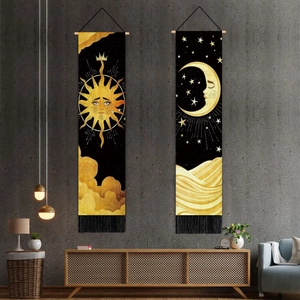 Close-up of sun and moon tapestries with wooden rods and tassels on concrete wall