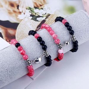 Macro shot of pink and matte black stone beads with heart magnetic clasp on velvet