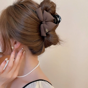 Elegant brown fabric bow hair claw clip styled on woman's hair in a side-rear view