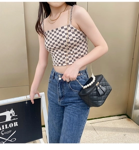 Quilted black crossbody bag with pearl handle and chain strap worn by a model