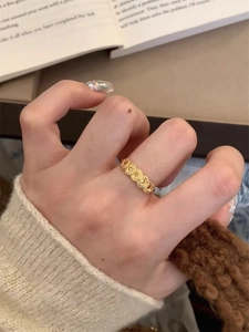 Detail of a 24k gold plated round coin open ring shown on a finger with warm aesthetic