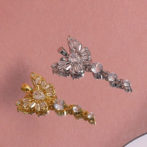 Macro shot of gold and silver butterfly pendants with crystals on a pink surface