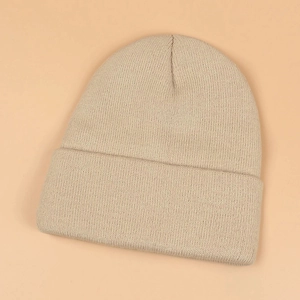 Close-up of beige knit beanie featuring thick woven texture and cozy winter fabric